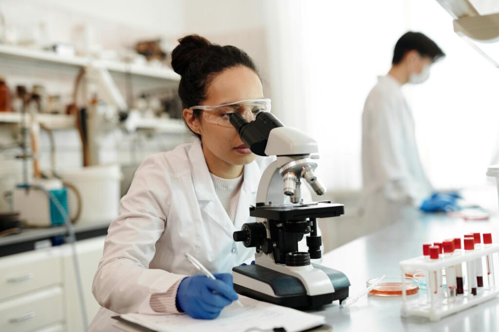Female scientist examining blood samples under a microscope in a laboratory.