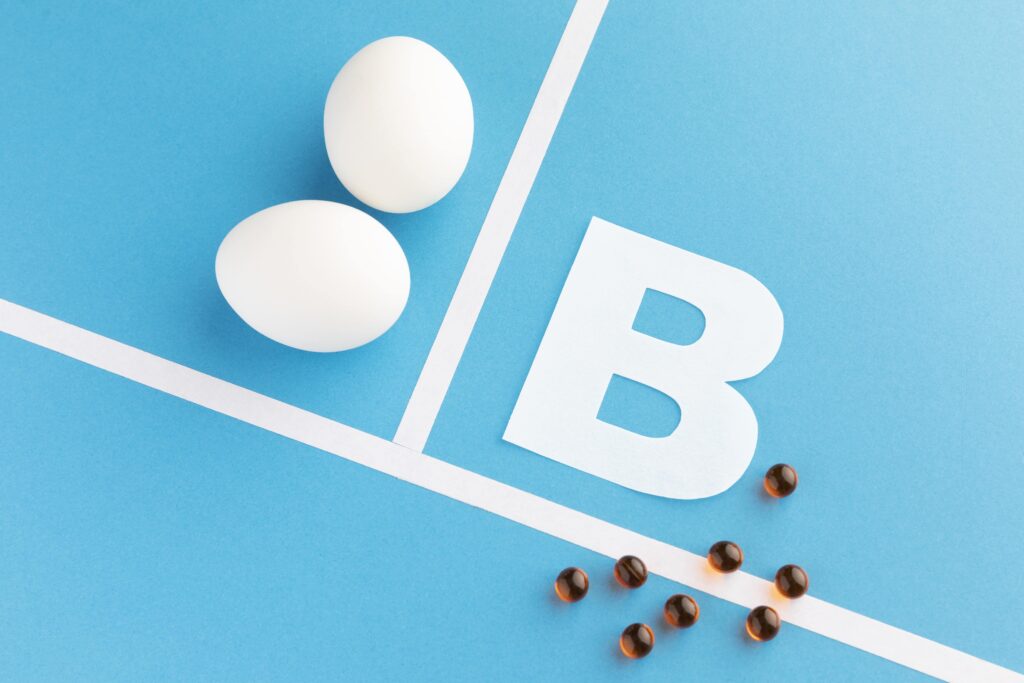 Two eggs and vitamin B capsules on a blue background