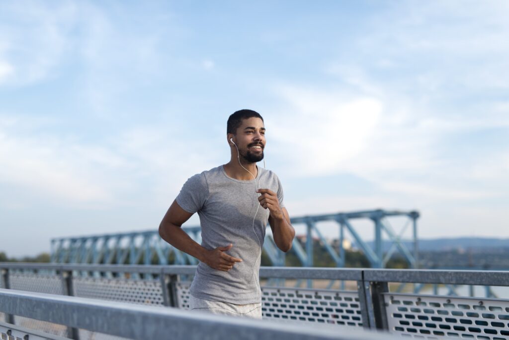 Young man jogging outdoors with headphones, promoting fitness and men's health