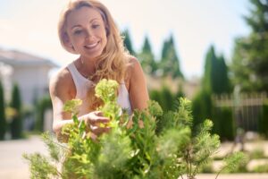 A women taking care of her garden flowers with a smile on her face.